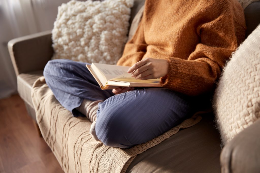 Woman reading book on couch in fall autumn