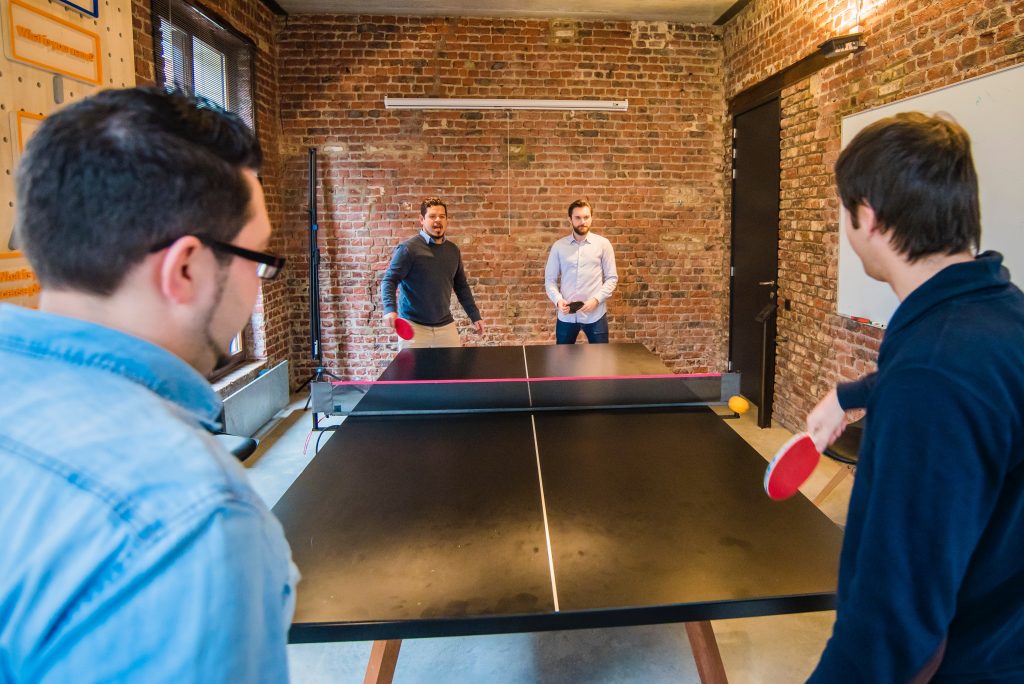 4 employees playing ping pong