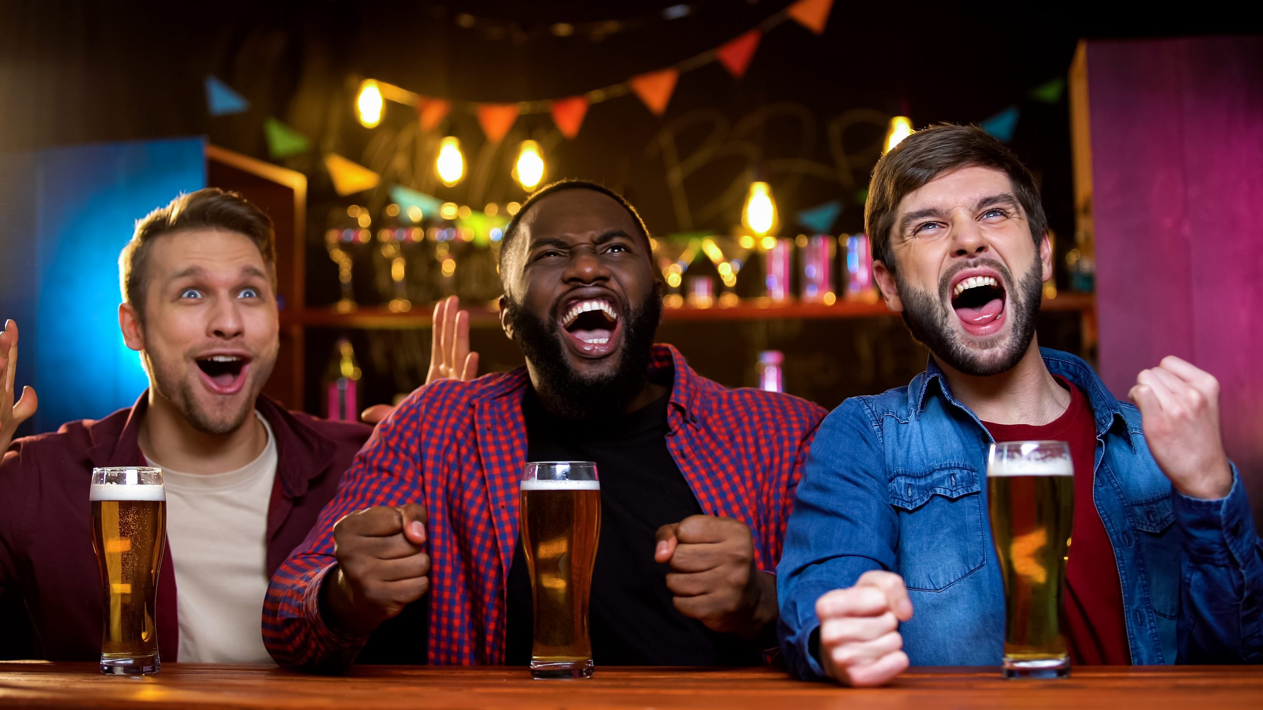 Three friends watching sports at a bar