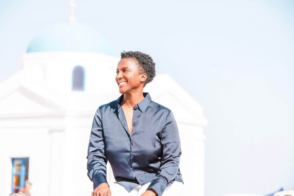 A smiling black woman poses in front of a church