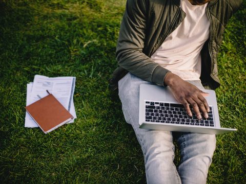 Man working on grass with laptop